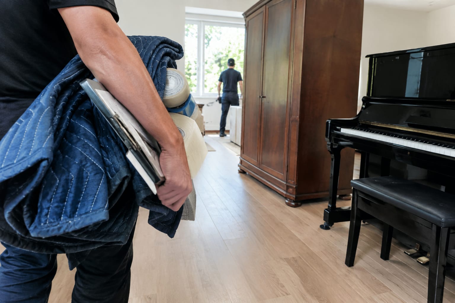 Hand pointing to the crew size line on a moving estimate beside a phone floor plan and tape measure