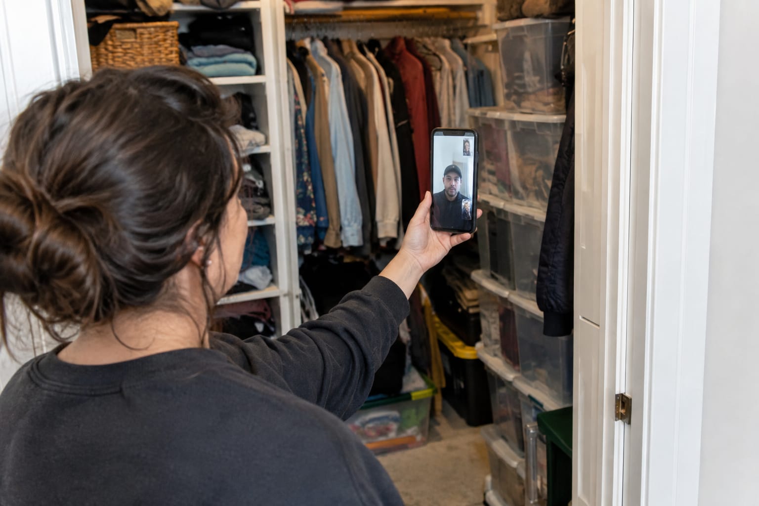 Homeowner on a video survey call showing a packed bedroom closet to an estimator on the phone screen.