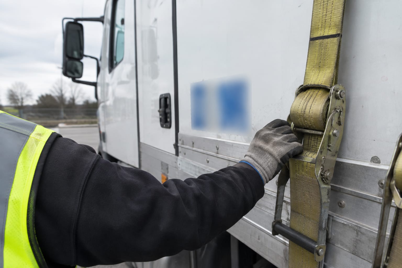 Close-up of a white truck cab door with a printed USDOT number decal on a city street